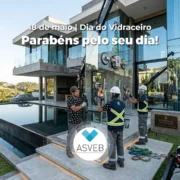 Três trabalhadores de construção, vidraceiros, fazendo içamento de um vidro jumbo em uma casa de luxo com piscina, usando um guindaste e ventosas para instalar uma grande vidraça.